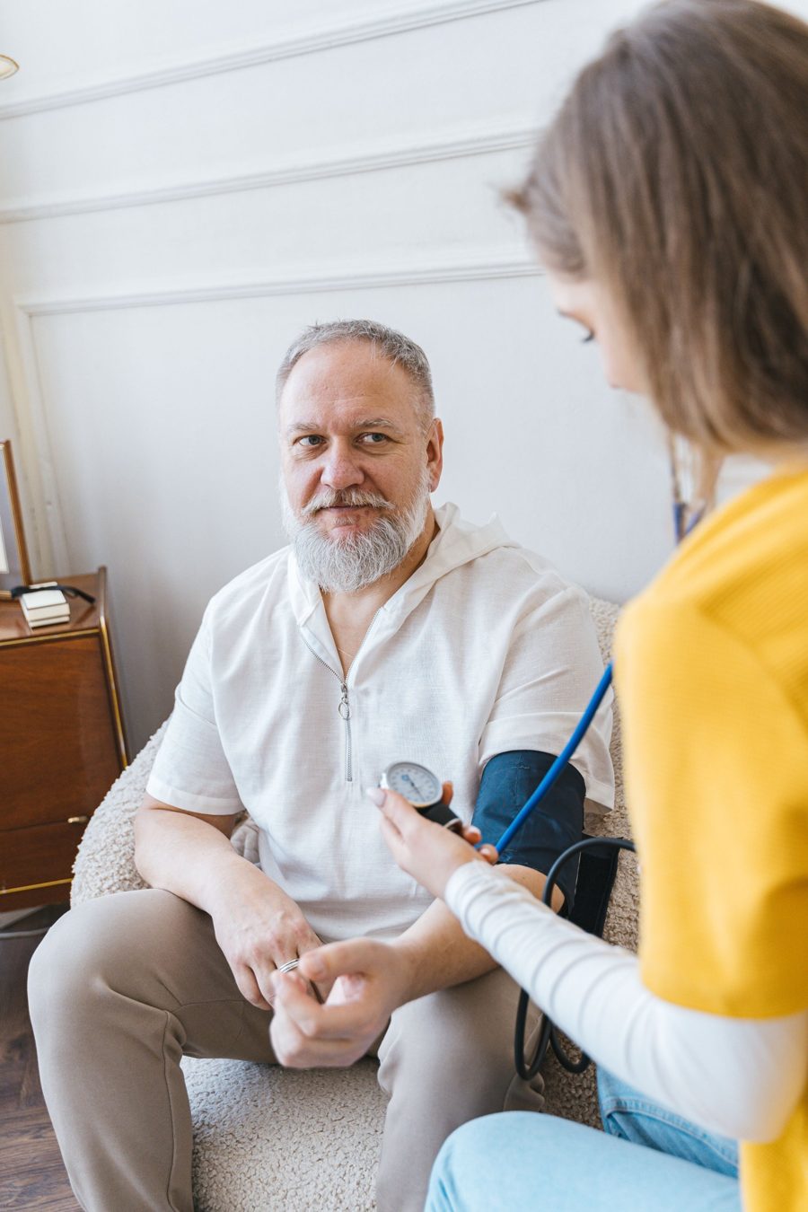 Nurse checking an older man's blood pressure at home